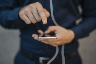 Businessman using smartphone with connected earphones