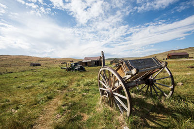 Abandoned cart on field against sky