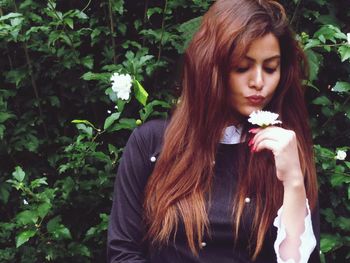 Beautiful young woman holding flower in hand.