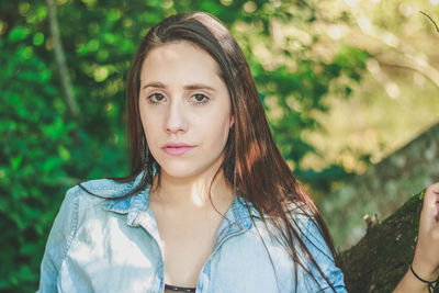 Close-up portrait of young woman against trees