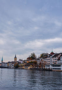 Buildings by river against sky