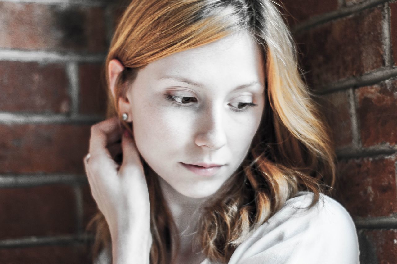 portrait, headshot, one person, young adult, hair, young women, real people, close-up, front view, lifestyles, brick wall, looking at camera, focus on foreground, hairstyle, beauty, blond hair, leisure activity, long hair, brick, beautiful woman, teenager, contemplation