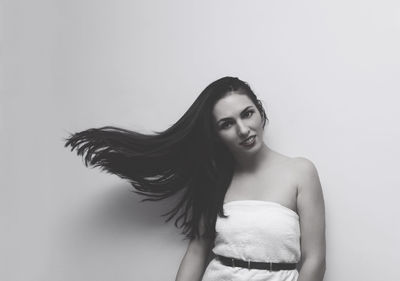 Portrait of young woman standing against wall