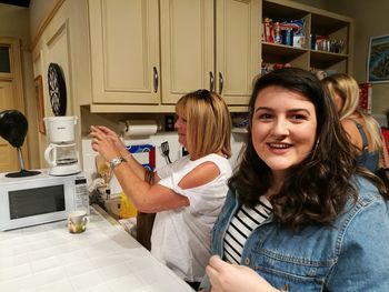 Portrait of smiling woman with mother in kitchen at home