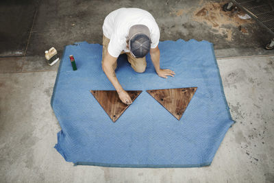 High angle view of carpenter polishing triangle shaped wood at workshop