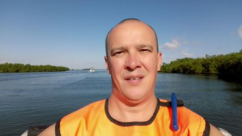 Close-up portrait of man on river against sky