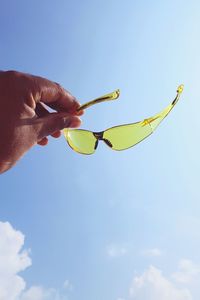 Midsection of person holding leaf against blue sky