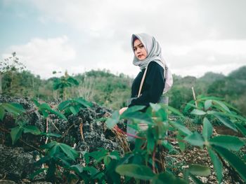 Young woman standing on field against sky