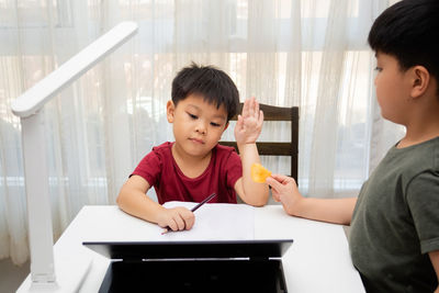 Full length of a boy sitting on table