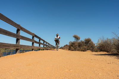 Black woman riding a bike on a sandy path in a sunny day