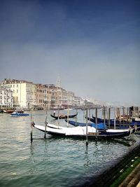 Boats moored on shore against clear sky