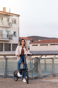 Woman looking at camera while riding an electric bike going home with copy space