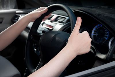 Cropped hand showing thumbs up sign while driving car