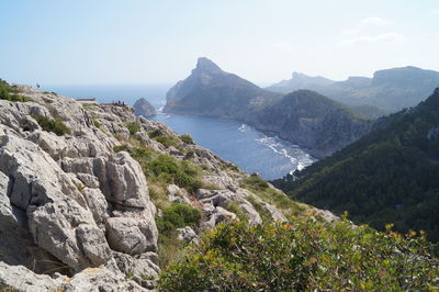 Scenic view of mountains by sea against clear sky