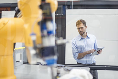 Businessman checking industrial robot in high tech company