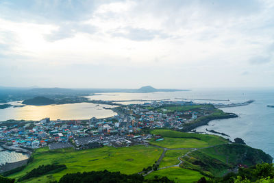 Townscape by sea against cloudy sky