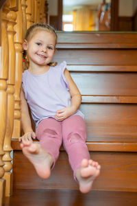 Portrait of cute baby boy sitting on hardwood floor