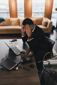 Stressed businessman sitting with head in hands at conference table in board room