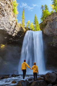 Rear view of man standing against waterfall