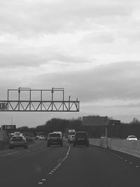 Vehicles on road against cloudy sky