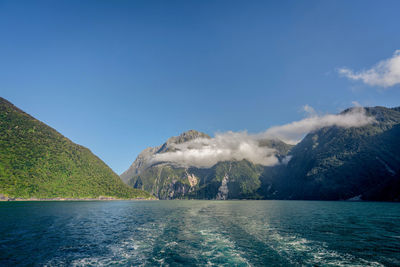 Scenic view of sea and mountains against blue sky