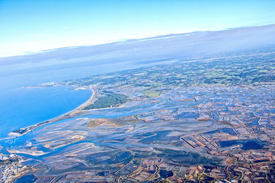 Aerial view of sea and cityscape against blue sky