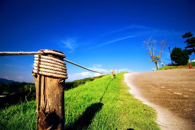 View of wooden post on field against blue sky