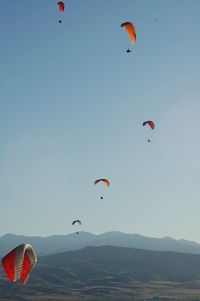 Parachutes flying over mountains against sky