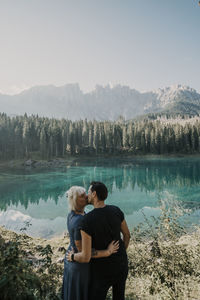 Rear view of couple on lake against mountains