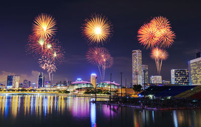 Firework display over illuminated buildings in city at night