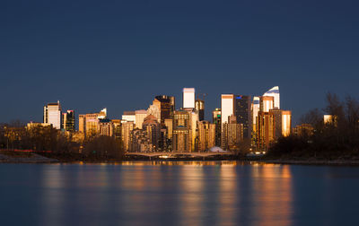 River by city buildings against clear sky