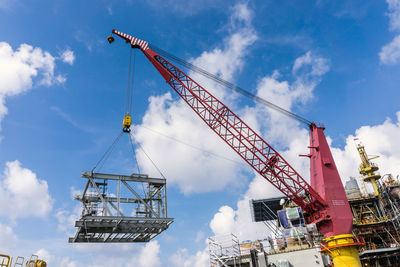 Low angle view of cranes at construction site against sky