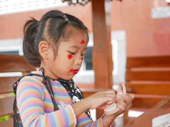 Close-up of cute girl applying paint on face