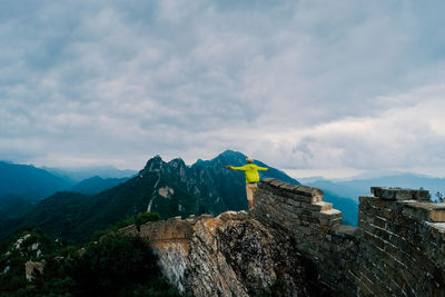 Rear view of man standing with arms outstretched against sky