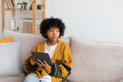 Portrait of young woman sitting on sofa at home