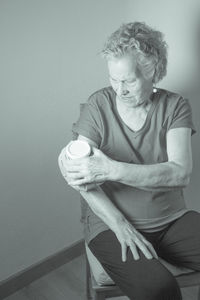 Woman holding ice pack on arm while sitting at home