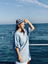 Young woman standing in sea against sky