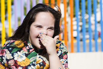 Teenager girl with down syndrome laughing, hand covering mouth