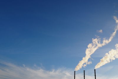 Low angle view of smoke stack against blue sky