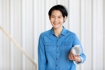 Portrait of a smiling young woman holding coffee cup