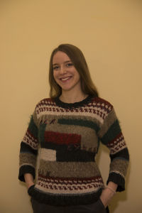 Portrait of smiling young woman standing against wall