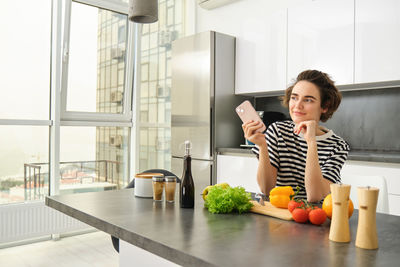 Young woman using mobile phone while sitting on table