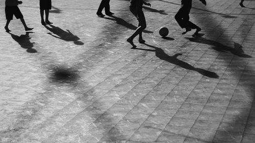 Low section of silhouette male friends playing soccer on floor