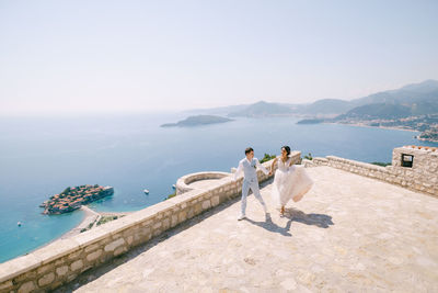 People looking at sea against sky