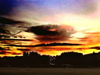 Silhouette trees against dramatic sky during sunset
