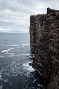 Rock formation by sea against sky