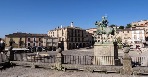 Buildings in city against clear blue sky