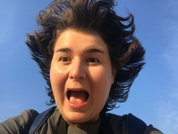 Close-up of woman screaming against blue sky