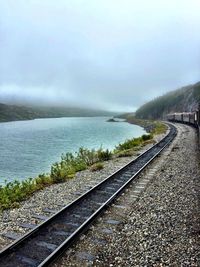 View of railroad tracks by sea against sky