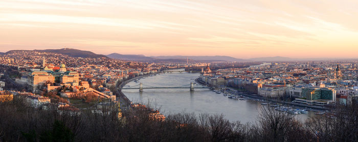 High angle view of river amidst buildings against sky during sunset